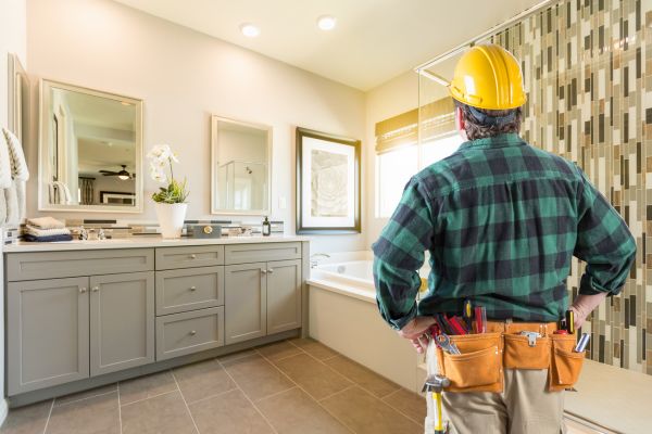 Contractor inspecting a modern bathroom renovation with new vanity, bathtub, and tiled shower Contractor inspecting a modern bathroom renovation with new vanity, bathtub, and tiled shower