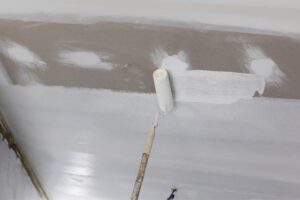 painter applying primer in ceiling