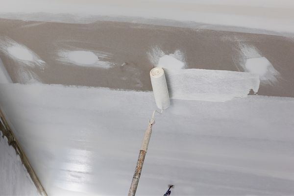 painter applying primer in ceiling painter applying primer in ceiling